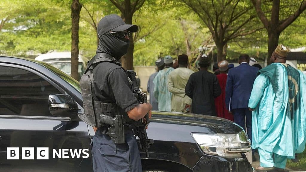 An armed officer in black with shades, cap and facemask stands guard outside the Federal High Court in Abuja on Wednesday 22 April 2026.